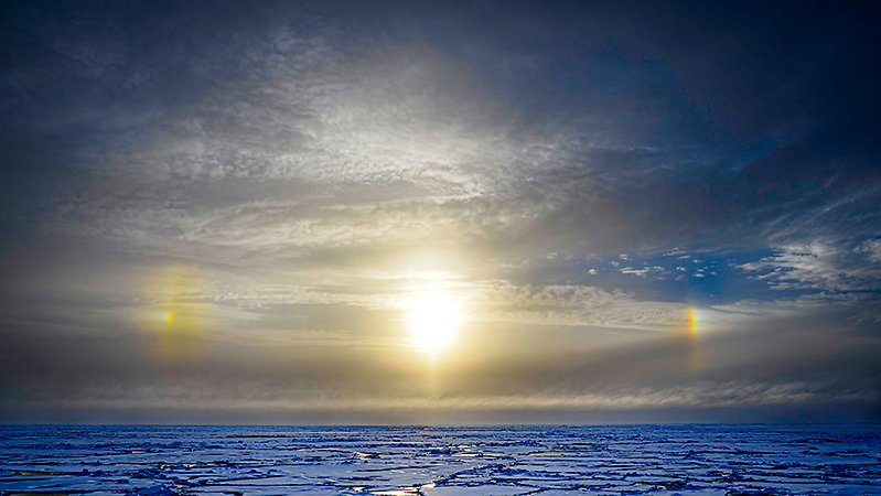 Sun, two sundogs, sky and ocean with ice.