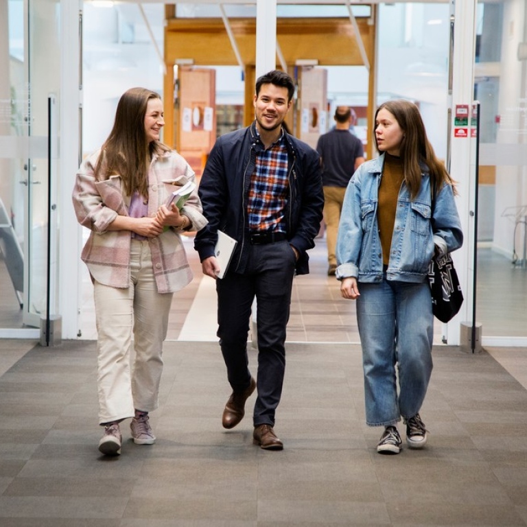Three students walking together in the library.